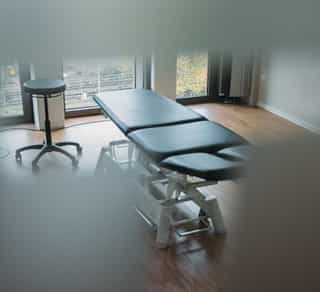 Zu sehen ist ein Einblick durch eine Milchglastür in einen kleinen Behandlungsraum von Physiosport Köln.