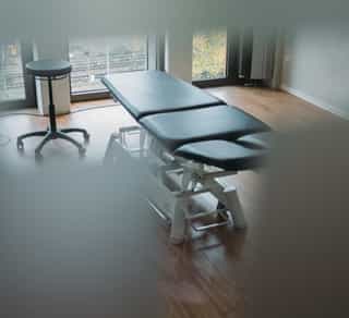 Zu sehen ist ein Einblick durch eine Milchglastür in einen kleinen Behandlungsraum von PhysioSport Köln.