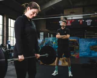 Frau beim Training mit Langhantel für den Oberkörper bei PhysioSport Köln.
