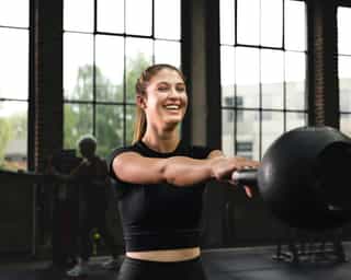 Frau beim Training an Geräten für den Oberkörper.