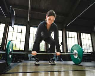 Frau beim Training mit Langhantel bei PhysioSport Köln.