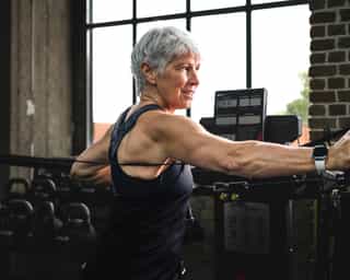 Frau beim Training mit Seilzug für Oberkörper an Geräten bei PhysioSport Köln.