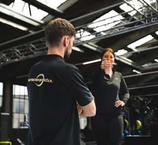 Physiotherapeut von PhysioSport mit einer Patientin. Er erläutert die Grundlagen zum Neuroathletiktraining.