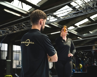 Physiotherapeut von PhysioSport mit einer Patientin. Er erläutert die Grundlagen zum Neuroathletiktraining.