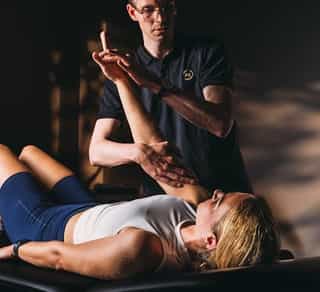 Physiotherapeut von PhysioSport Köln behandelt die Beweglichkeit der Schulter einer Patientin.