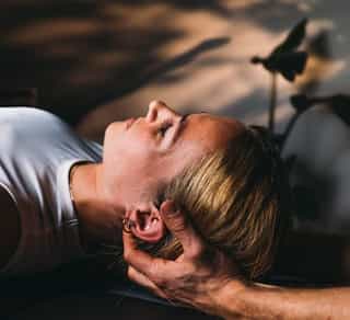 Zu sehen ist eine Patientin von schräg seitlich mit einem Physiotherapeuten während einer CMD Behandlung bei PhysioSport Köln.