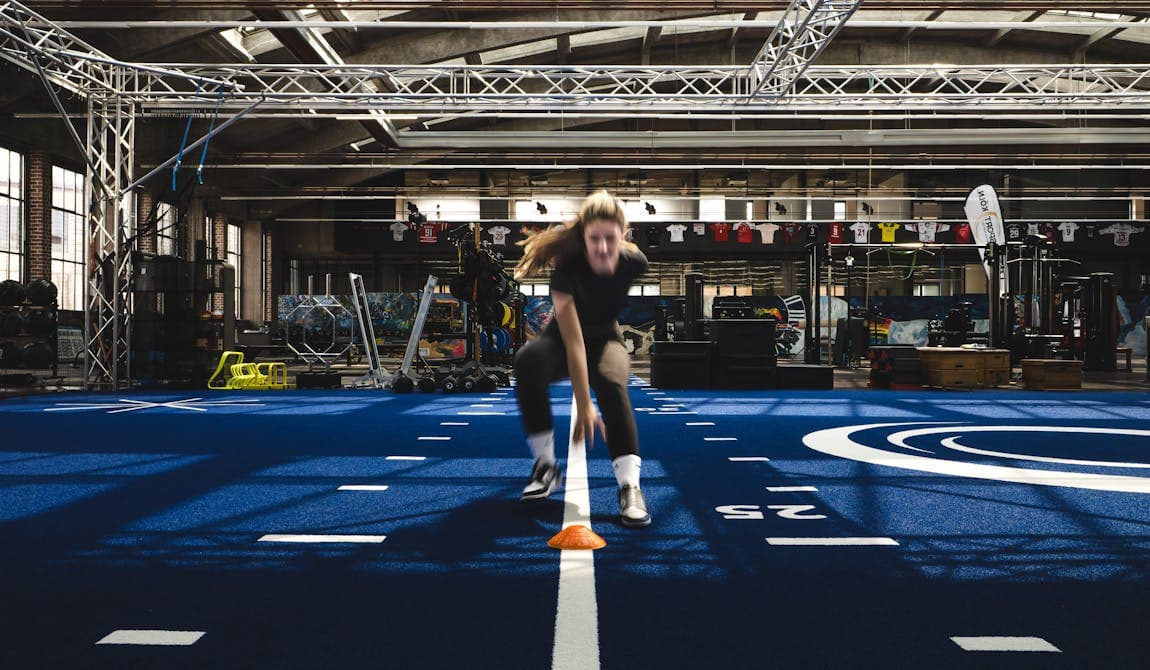 Sportlerin beim Sprint- und Koordinationstraining mit Hütchen in der Trainingshalle von Physiosport Köln.