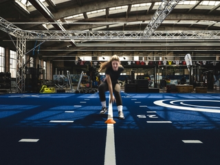Sportlerin beim Sprint- und Koordinationstraining mit Hütchen in der Trainingshalle von Physiosport Köln.