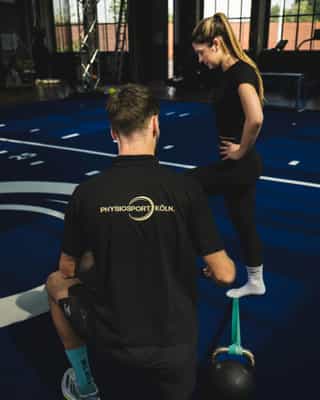 Trainer von Physiosport Köln erläutert Sportlerin Kraftübungen für die Verbesserung der Beinkraft.