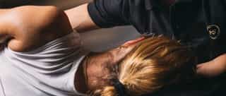 Patientin liegt auf Liege bei PhysioSport Köln, männlicher Therapeut führt eine Diagnose der Schmerzen nach Schulterluxation durch.che Behandlung an der Wirbelsäule durch.