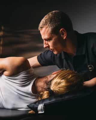 Trainer mobilisiert Hüftmuskulatur einer Patientin bei PhysioSport Köln.