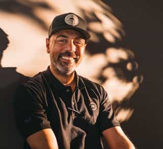 Das Bild zeigt einen Mitarbeiter von PhysioSport Kölan, der lächelnd auf einem Fahrrad sitzt.