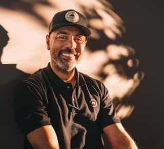 Das Bild zeigt einen Mitarbeiter von Physiosport Kölan, der lächelnd auf einem Fahrrad sitzt.