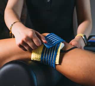 Physiotherapeutin von PhysioSport legt Patientin Elektroden am Knie für Elektrotherapie in der Physikalischen Therapie an.