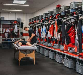 Zu sehen ist ein Einblick in die Mannschaftskabine der Kölner Haie, den Partnern von Physiosport Köln. In der Mitte steht eine Liege mit einem daraufliegendem Spieler, der behandelt wird.