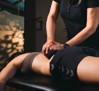 Physikalische Therapie bei PhysioSport: Wärmetherapie mit Wärmekissen am Rücken einer Patientin.