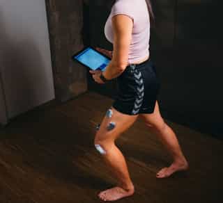 Patientin bei PhysioSport hält Gerät während Physikalischer Therapie mit EMG-Messung.