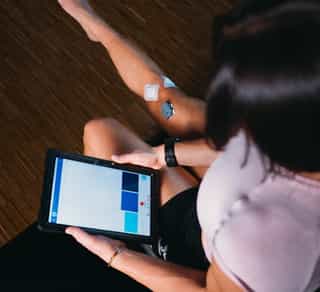 EMG in der Physikalischen Therapie bei PhysioSport, Patientin beobachtet Daten auf Handgerät.