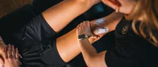 Physiotherapeutin von PhysioSport Köln behandelt liegenden Patienten nach kreuzbandriss mit Elektrotherapie.