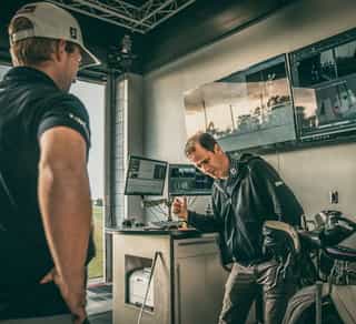 Zu sehen ist ein Golfspieler und ein externer Trainer beim Analyseprozess zur Verbesserung seiner Leistung mittels TPI-Golfscreening durch PhysioSport Köln.