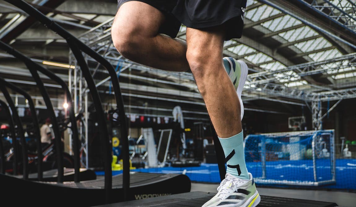 Zu sehen ist ein Sportler auf einem Laufband bei PhysioSport Köln. In Nahaufnahme das Knie.