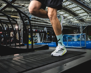 Zu sehen ist ein Sportler auf einem Laufband bei PhysioSport Köln. In Nahaufnahme das Knie.