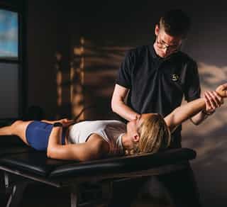 Physiotherapeut von PhysioSport Köln untersucht das Schultergelenk einer Patientin aus die allgemeine Beweglichkeit hin.