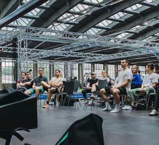 Zu sehen ist eine Trainerin von Physiosport, die einer Gruppe von Sportlern die Inhalte von PACE Athletiktraining theoretisch vermittelt.