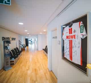 Zu sehen ist der Durchgangsbereich von PhysioSport Köln, Standort Mediapark, mit Spezialisten für die Behandlung von Schulterluxationen.