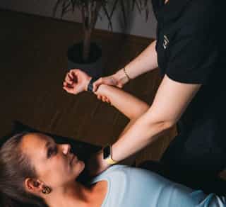Zu sehen ist eine Physiotherapeutin von PhysioSport Köln bei der Behandlung einer Patientin mit Impingement Schulter.