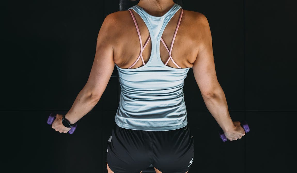 Zu sehen ist eine Sportlerin von hinten, insbesondere der Rücken, bei einem speziellen Rückentraining bei PhysioSport Köln.