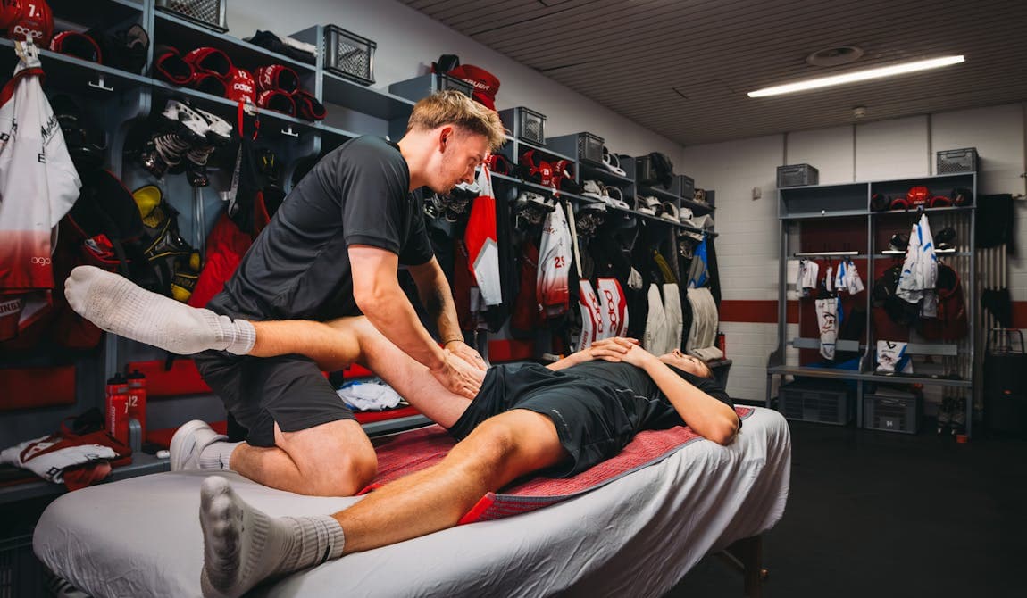 Profisportler auf einer Behandlungsliege wird von einem Physiotherapeuten von Physiosport Köln nach Muskelverletzung behandelt.