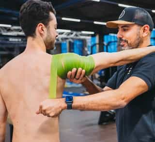 Sportler wird von einem Physiotherapeuten von PhysioSport Köln an der Schulter behandelt.