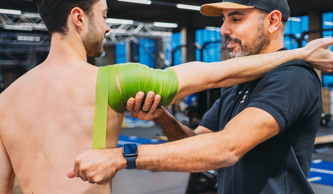 Sportler wird von einem Physiotherapeuten von PhysioSport Köln an der Schulter behandelt nach Schulterluxation.