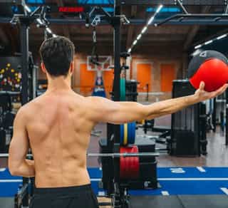 Zu sehen ist ein Sportler in der Trainingsanlage von PhysioSport Köln. Er steht mit Basketball bei der Analyse der Beweglichkeit nach Rotatorenmanschettenruptur.