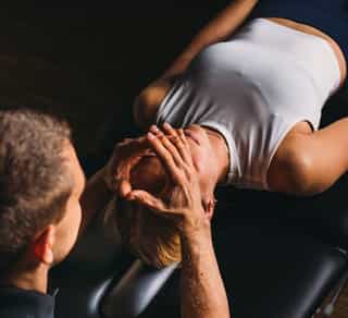 Zu sehen ist eine Patientin von schräg seitlich mit einem Physiotherapeuten während einer CMD Behandlung bei PhysioSport Köln.