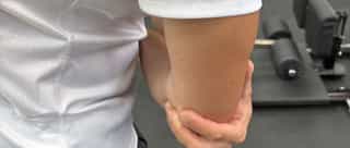 Zu sehen ist ein Sportler mit Schmerzen am Ellenbogen, Tennisellenbogen Behandlung bei PhysioSport Köln.