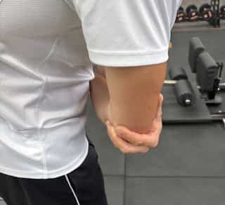 Zu sehen ist ein Sportler mit Schmerzen am Ellenbogen, Tennisellenbogen Behandlung bei PhysioSport Köln.