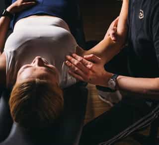 Physiotherapeut von PhysioSport Köln behandelt eine Sportlerin mit namueller Therapie im rechten Schulterbereich.