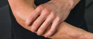 Sportler mit Schmerzen im Ellenbogen nach Überlastung im Sport.