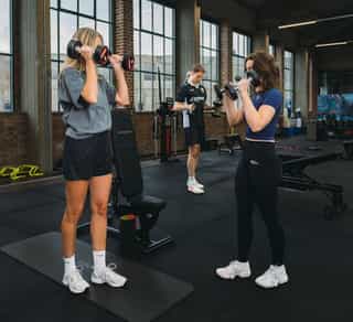 Zwei Sportlerinnen mit Trainer im individuellen Training bei PhysioSport Köln nach Schulterbeschwerden.