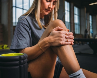 Sportlerin fasst sich ihr rechtes Knie aufgrund von Knieschmerzen.